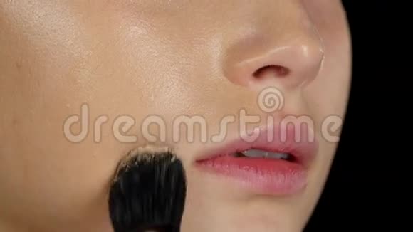 化妆师在模特的脸上涂上遮瑕膏黑色的特写视频的预览图