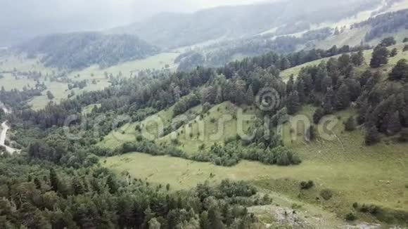 空中观景台飞越一片绿草如茵的岩石山在美丽的云彩中飞过高山视频的预览图