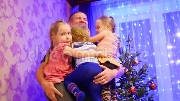 快乐的父亲牵着孩子们的手在一个圣诞节的晚上笑着在背景灯光和视频的预览图