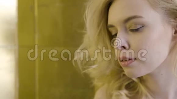 漂亮的金发女人的脸贴上行动一个美丽的金发女人在阳光下的特写视频的预览图