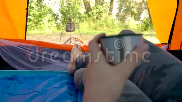 帐篷里的女人喝热茶水壶在她面前的炉火上加热视频的预览图