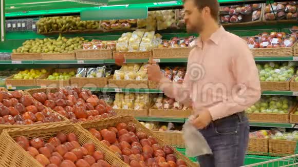 在杂货店里挑选新鲜红苹果的男人视频的预览图