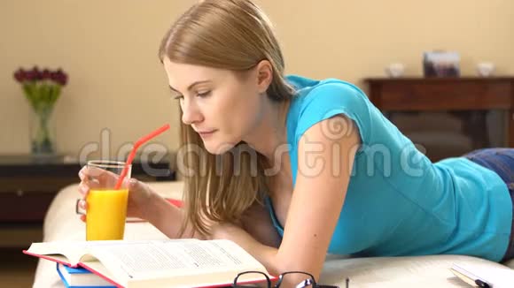 漂亮的大学生戴着眼镜躺在沙发上学习喝橙汁视频的预览图