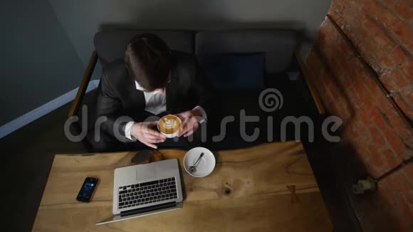 商人在笔记本电脑上工作在咖啡馆里喝咖啡顶部视图视频的预览图