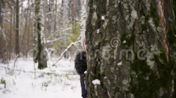 冬天公园里女孩从树后扔雪球视频的预览图