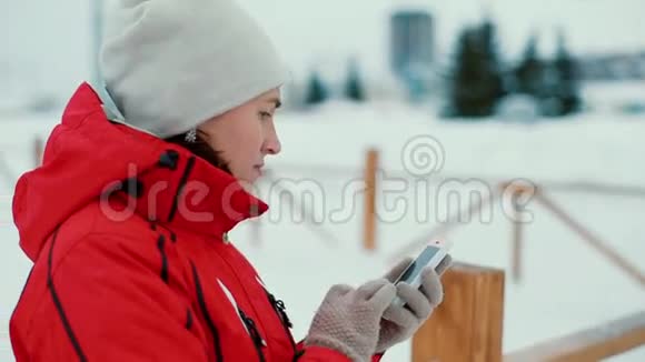 迷人的女人在冬天的风景户外用手机发短信视频的预览图