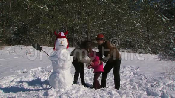 爸爸妈妈和小女儿在森林附近的草地上堆雪人视频的预览图
