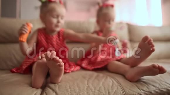 两个穿着迷人红色连衣裙的小双胞胎姐妹光着脚在房间里欢快地吹着肥皂泡视频的预览图