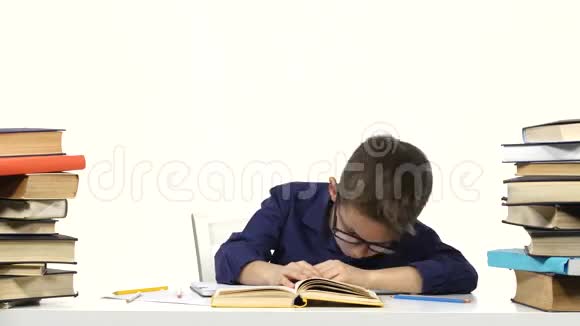 小男孩坐在桌子旁慢慢地读这本书白色背景视频的预览图
