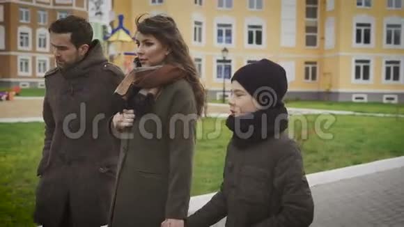 亲近幸福的父亲母亲和儿子一起散步一家人穿着暖和的衣服一起走在视频的预览图