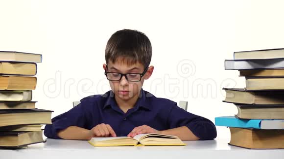 小男孩坐在桌子旁慢慢地读这本书白色背景视频的预览图