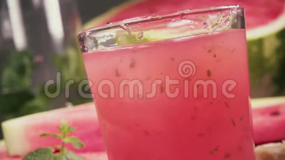 在西瓜的背景下用玻璃杯喝慢动作的西瓜视频的预览图