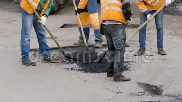 在街道修复工程中铺设碎石沥青的工人视频的预览图