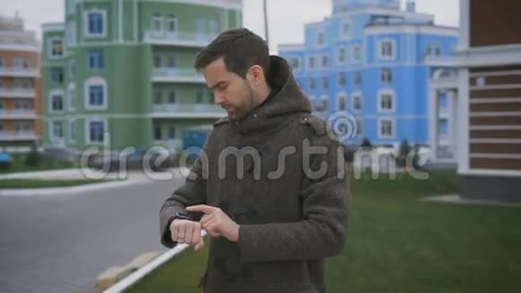 一个穿灰色外套的人手上拿着一个钟手指上拿着一个戒指在他家的院子里他改变了视频的预览图