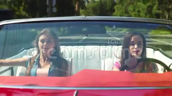 两个年轻快乐的女孩驾驶一辆敞篷车视频的预览图