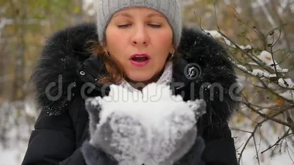 女孩慢慢地用双手特写来吹雪视频的预览图