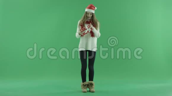 戴着圣诞帽的迷人年轻女人看着她的圣诞礼物背景上的彩色钥匙视频的预览图