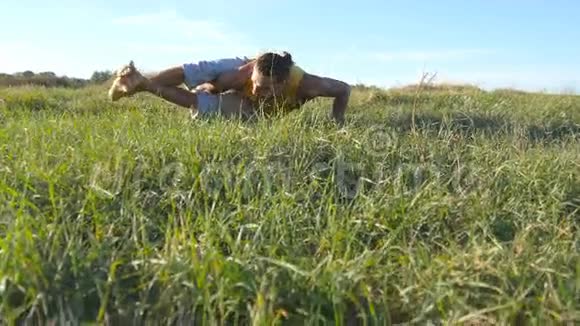 年轻的运动男子练习困难的瑜伽姿势在自然在草地上做瑜伽动作和姿势的白人视频的预览图