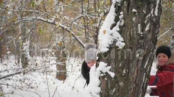 一家人在冬天的公园里从树后扔雪球视频的预览图