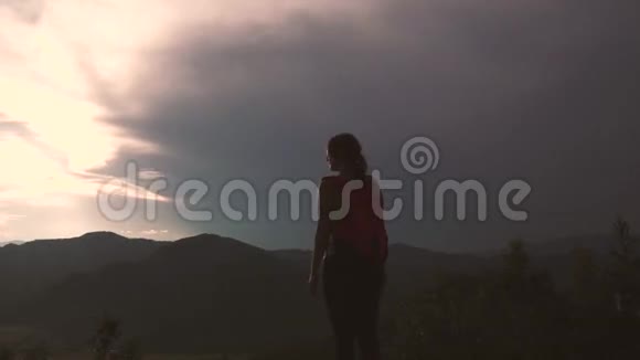 山顶上的女游客年轻女子欣赏日落和令人叹为观止的景色背包旅行者视频的预览图