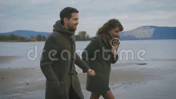 浪漫的一对夫妇沿着海滨奔跑跳跃快乐的人都牵着手在一起青年视频的预览图