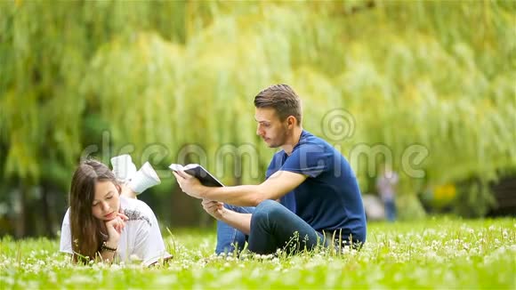 年轻夫妇躺在草地上轻松地看书视频的预览图
