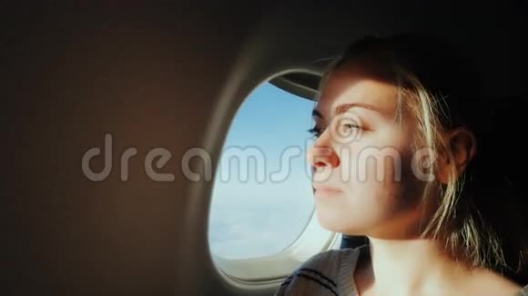 年轻女子坐飞机飞行坐在敞开的窗户前可以在天空中看到视频的预览图