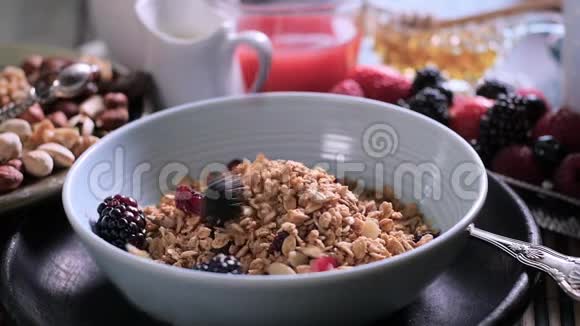 慢动作视图浆果落在一碗谷类食品上早餐吃干水果视频的预览图