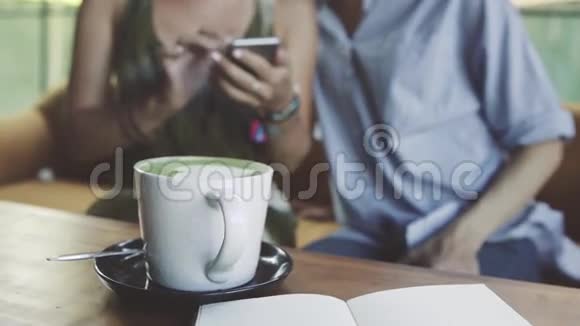 两个女性朋友使用智能手机桌子上有蛋糕和一杯拿铁视频的预览图