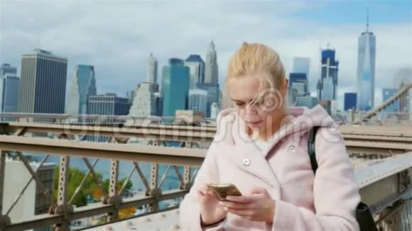 一个年轻的女人使用智能手机纽约布鲁克林大桥城市背景视频的预览图