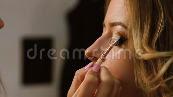 化妆师把化妆涂在女孩的脸上她画了眼影视频的预览图