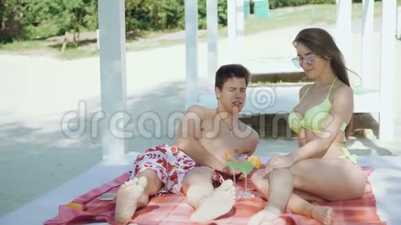 快乐的一对夫妇在海滩上休息边说边碰杯边喝鸡尾酒视频的预览图