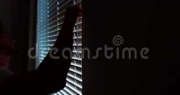 醒来后男人透过窗户看百叶窗视频的预览图