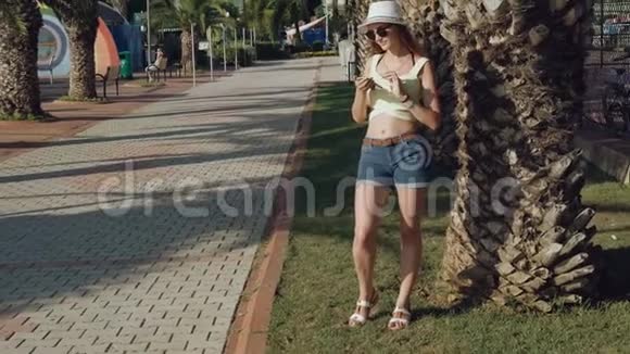 在炎热的夏天时尚女孩在街上使用手机视频的预览图