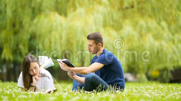 年轻夫妇躺在草地上轻松地看书视频的预览图