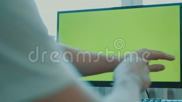 后景一中年男子坐在大屏幕显示器前绿色屏幕键盘视频的预览图