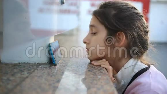 悲伤的女学生坐在街上看着她的电话等待一个电话视频的预览图