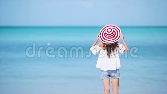 在热带海滨玩得很开心的年轻美女快乐的女孩以蓝天和碧蓝的海水为背景视频的预览图