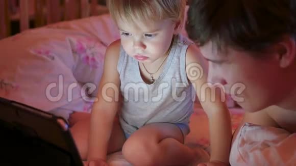 晚上和父亲一起在平板电脑上看动画片的小孩视频的预览图