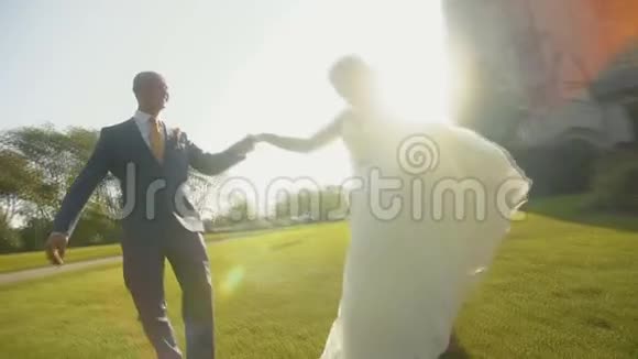 布鲁内特新娘和英俊的男子在绿草上旋转互相享受视频的预览图