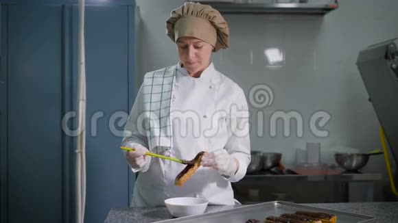 糖果师在刚出炉的蛋糕上轻轻涂抹厚厚的一层巧克力在她最喜欢的工作期间视频的预览图