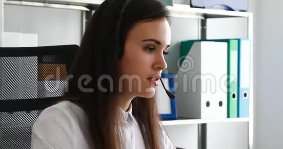 女人在耳机上说话在现代办公室里使用笔记本电脑视频的预览图
