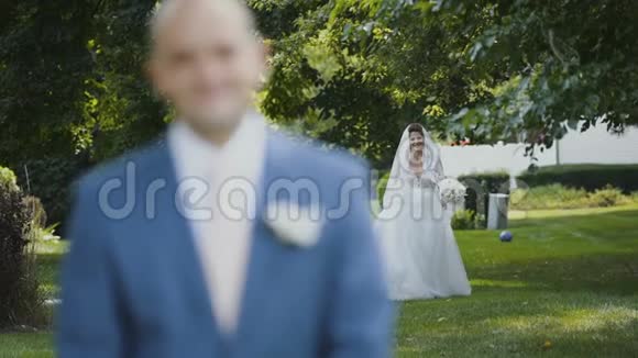 迷人的新娘带着迷人的花束前往绿色公园的新郎视频的预览图
