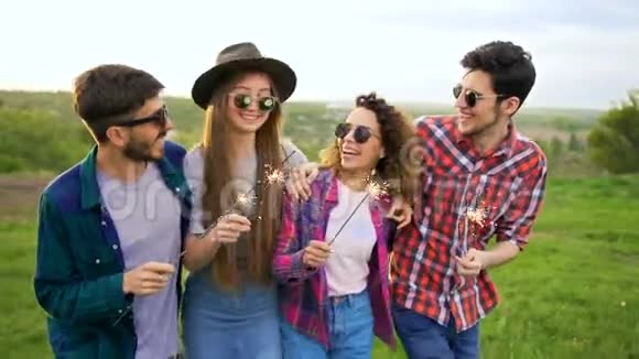四个快乐微笑的朋友在慢动作中带着火花走着夏日休闲理念视频的预览图