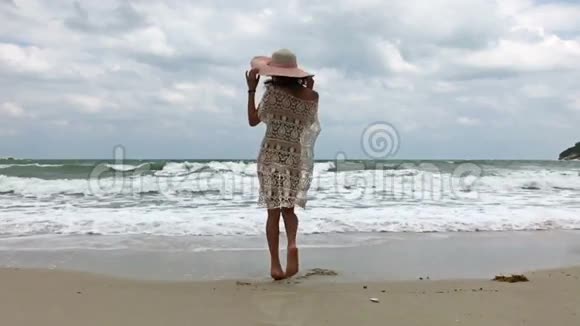 美丽的女孩戴着大帽子在海滩上扭来扭去视频的预览图