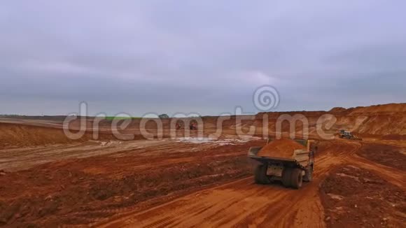 重型卡车沿采砂场行驶自卸卡车的空中视野视频的预览图
