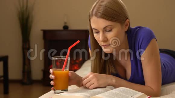 年轻迷人的美女躺在沙发上喝着果汁看书视频的预览图