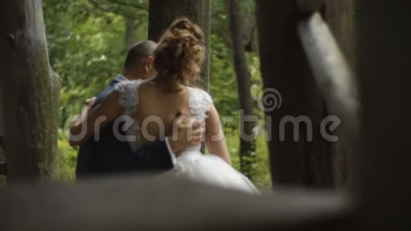 新婚之日年轻漂亮的新娘和新郎坐在森林里沐浴视频的预览图