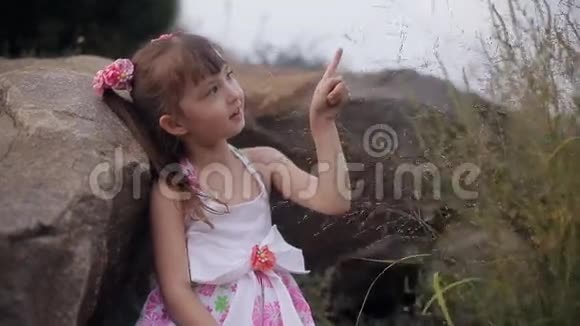 山里的小女孩坐在巨大的石头中间玩着植物视频的预览图