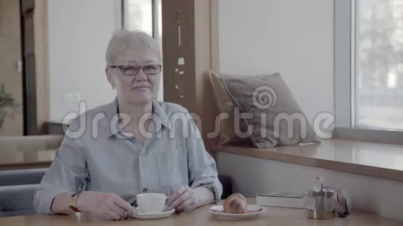 一个成熟的女人在时尚的咖啡馆里喝杯茶的肖像视频的预览图